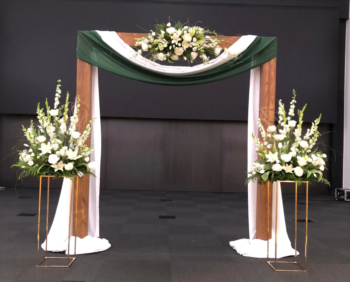 Three simple white flower arrangements to make your wedding ceremony special. Add a wooden arch and two gold risers to elevate these three simple pieces to the next level, and Voilà. You now have the perfect setting for your wedding day. 